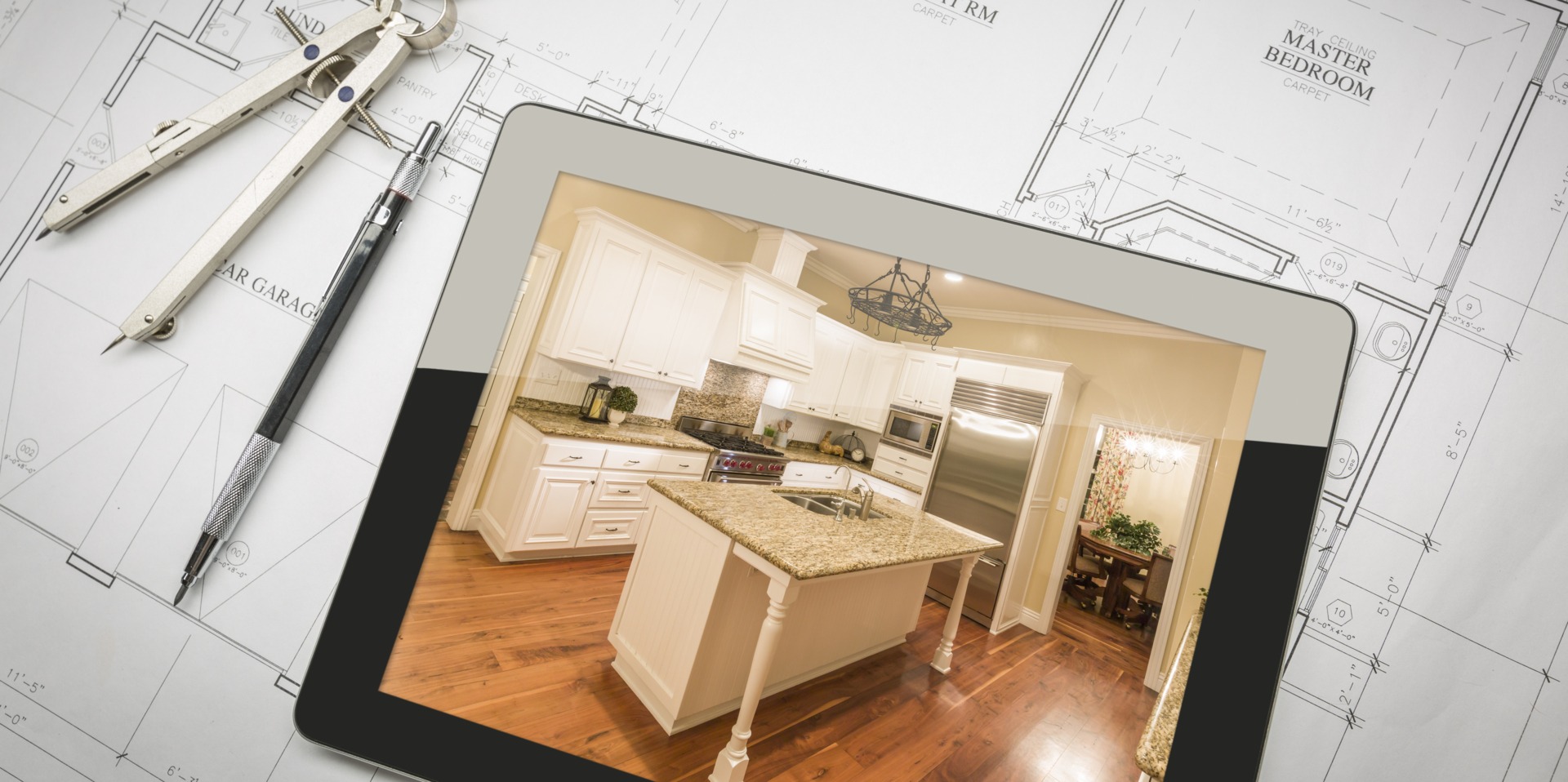 Blueprints and tools surround a tablet displaying a modern kitchen interior, highlighting design ideas for renovation or planning.